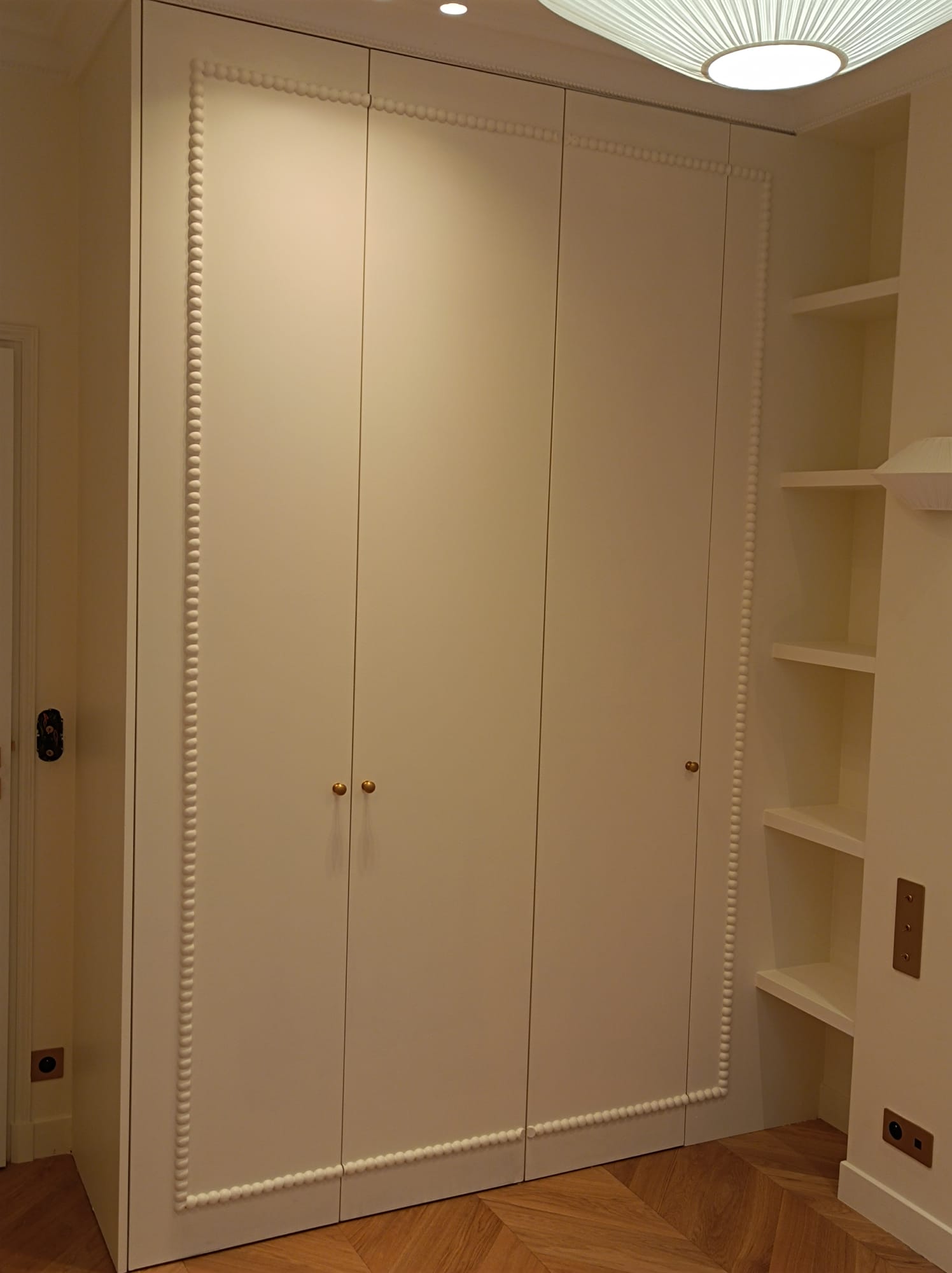 Placard sur mesure mouluré, boutons laiton, parquet chevron