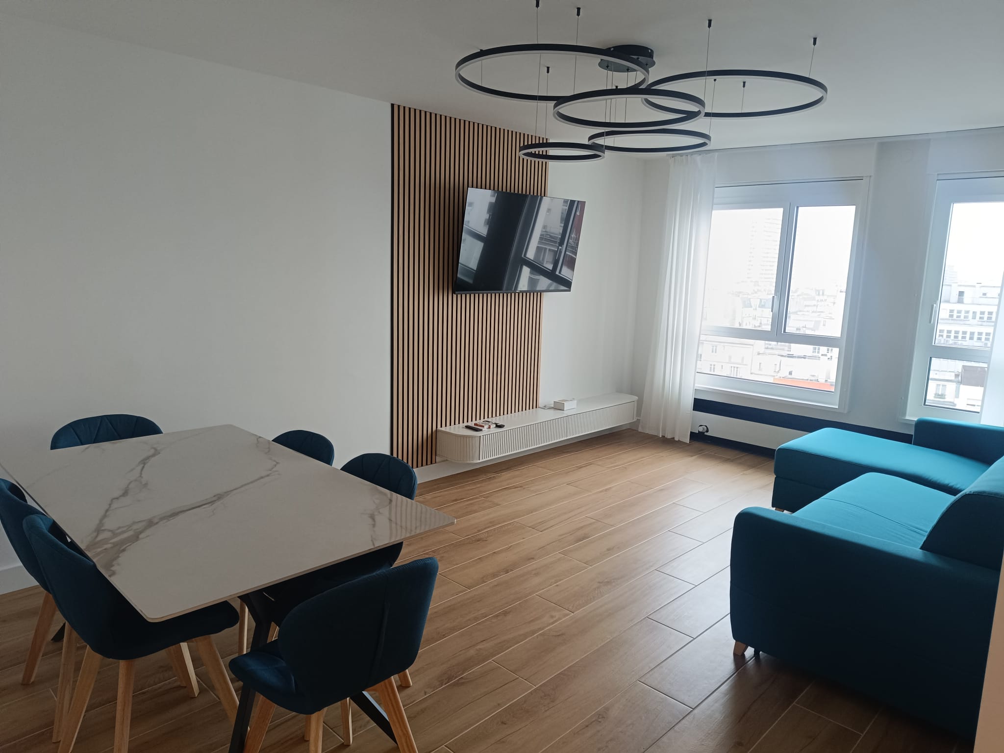 Séjour rénové, mur en tasseaux de bois et lustre
